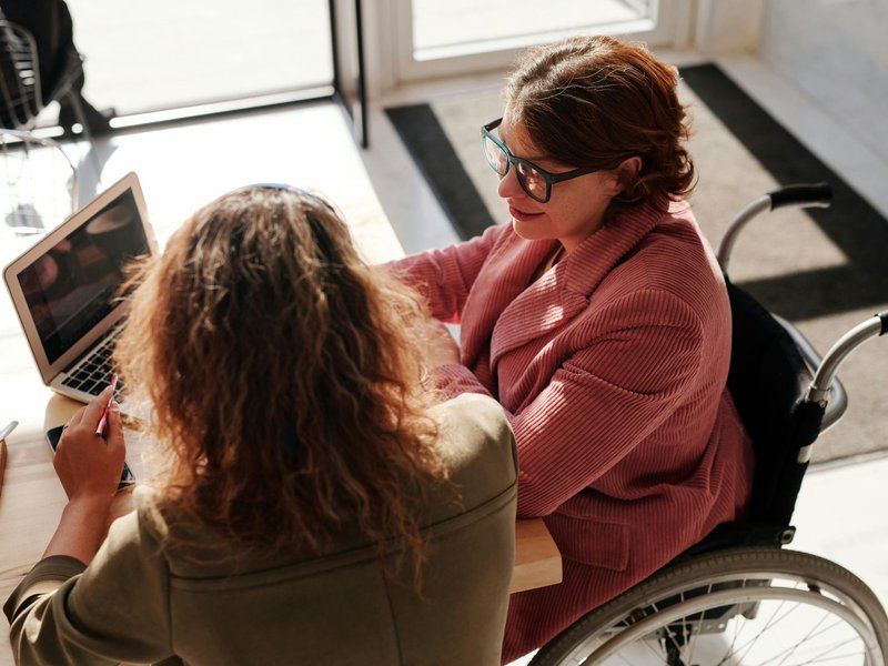 A claimant using a wheelchair meeting with an advisor over a laptop