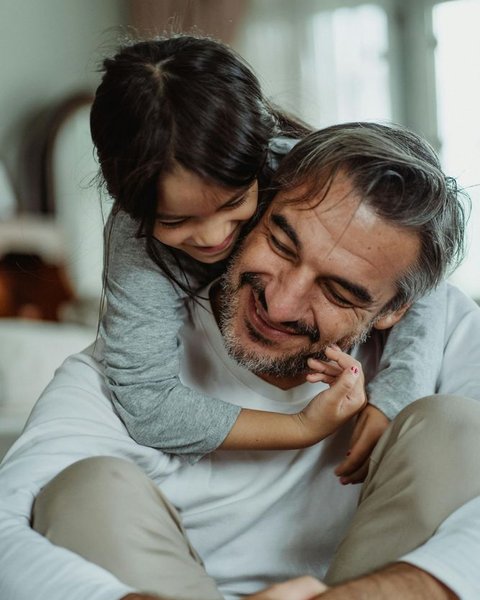 A father laughing with his young daughter at home