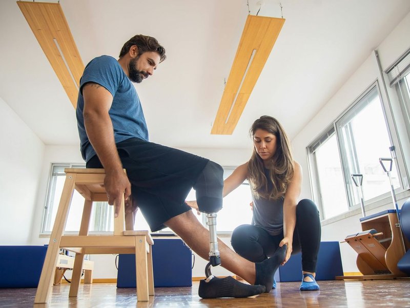 A physical therapist helping a client adjust his prosthetic leg