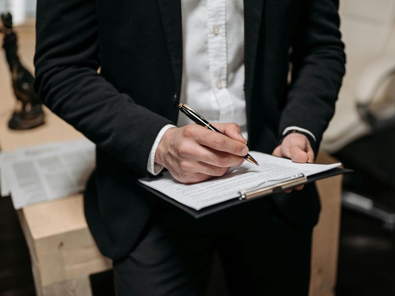 An attorney signing legal paperwork on a clipboard